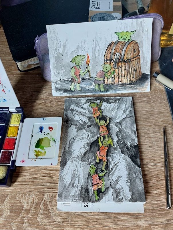 watercolour drawings of goblins on a table next to watercolor pallette and brush